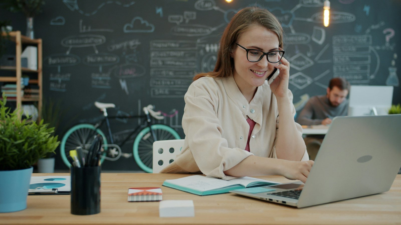 Woman on the phone while working on a laptop in an office